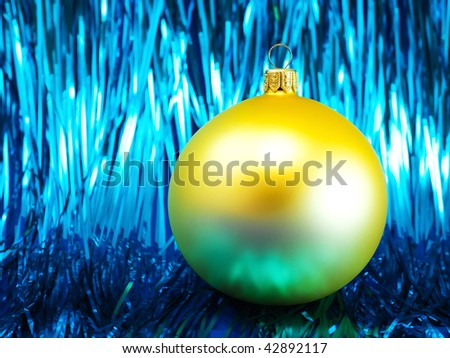 Yellow Christmas bauble on a shiny blue glitter background