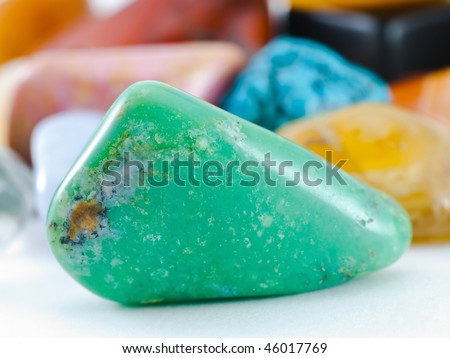 Polished green nephrite gemstone in front of gemstone collection
