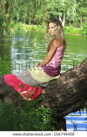 Sexy girl sitting on a tree by a river