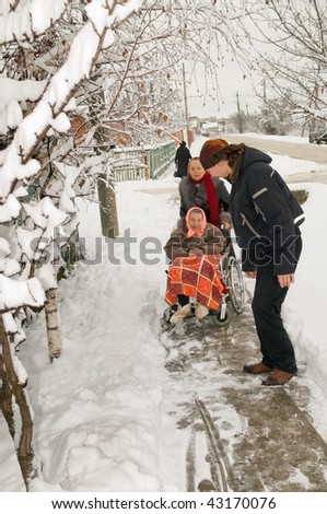 The young man helps to pull out an invalid carriage from a snowdrift. A family on walk.