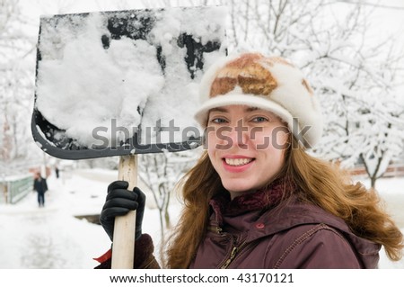 The young woman cleans snow from sidewalk.