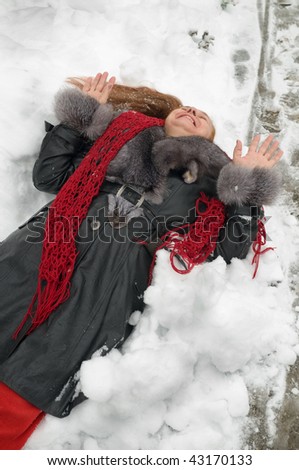 The woman has fallen to white fluffy snow and laughs.
