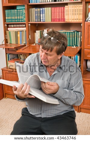 The elderly man thumbs through the book from house library.