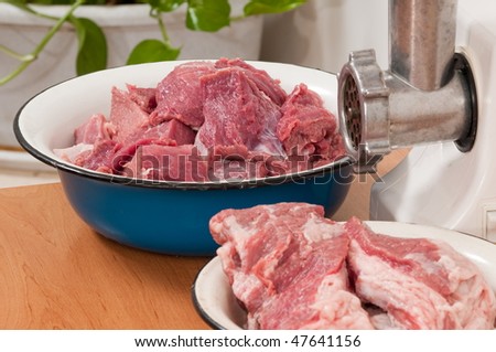Meat pieces prepared for forcemeat and an electrical meat grinder.