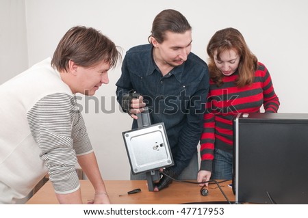 Two men and one woman prepare the new computer for operation.