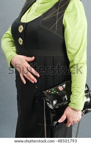 The elderly woman in a green jacket and a black dress with a ladies\' bag.