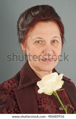 The elderly woman and white rose. Seventy years.