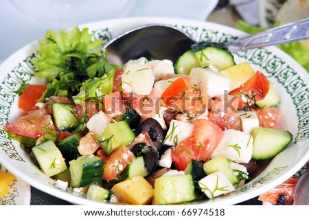 Vegetable salad with olives and cheese in a soup plate.