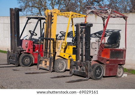 Three electric loaders for work in a warehouse.