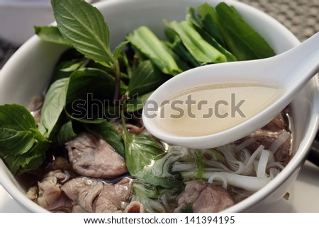 Asian, Vietnamese inspired noodle dish, Pho. Dish made with rice noodles, strips of beef, in a spicy aromatic beef broth with ginger, garlic, red chiles and topped with basil, cilantro and lime.