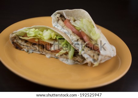 Chicken Shawarma. Pita bread filled with shawarma seasoned grilled chicken, beef, or lamb patty topped with lettuce, tomatoes, onions, pickles, parsley and tahini sauce