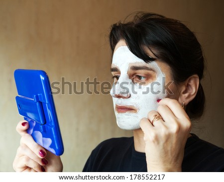 young beautiful woman gets cosmetic mask in the mirror