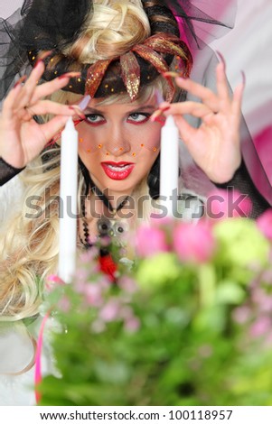 beautiful bride wearing black net gloves and unusual hat touches two white candles
