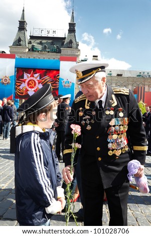 MOSCOW - MAY 9: World War II veteran of Navy in uniform with  carnations in the hand talks with boy in the peakless cap on Red Square on Victory Day, May 9, 2011, Moscow, Russia.
