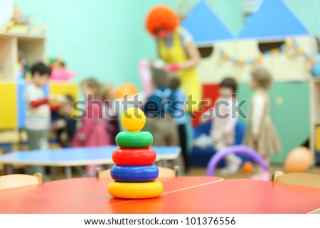 Colorful pyramid toy stand at table in kindergarten; children play