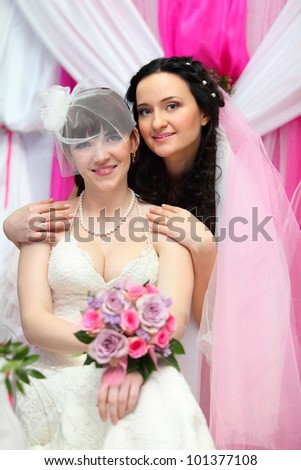 Happy bride stands behind other bride and put hands on her shoulders; Focus on women on right