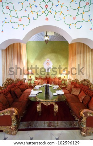 beautiful table with serving and red sofas in separate room inside eastern luxury restaurant