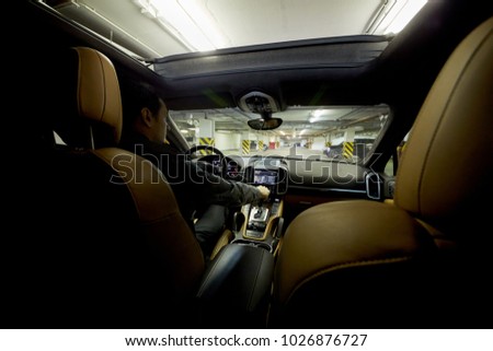 Man drives car at underground parking, view from backseat.