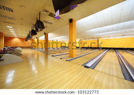 Empty bowling club, lot of bowling lanes with skittles, yellow walls and floor