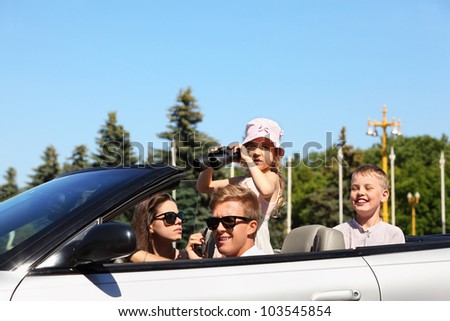 Beautiful father, mother and two children ride in convertible car and play spies