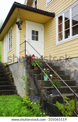 White door and stairs of Norway house, flowers are in pots on steps