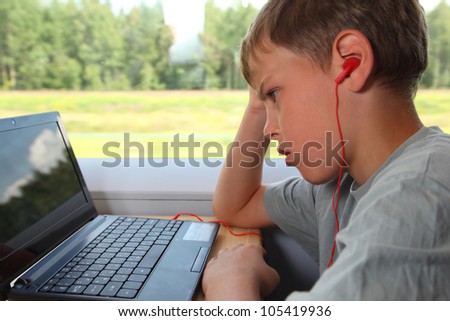 one boy watches movie on laptop in train