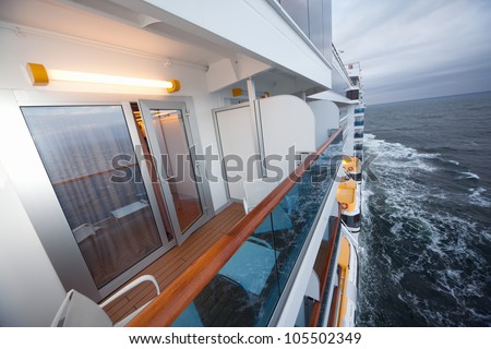 balcony with chairs table lamp on ship with view on sea in evening