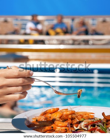 woman on deck eating seafood cocktail with fork near pool