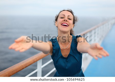 Beautiful woman stands on board of large ship and reaches out to viewer