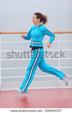Healthy woman wearing in blue sports suit runs on cruise liner deck