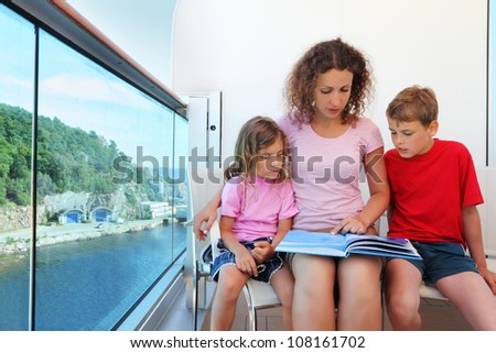 Mother, daughter and son carefully review book on cruise liner deck.