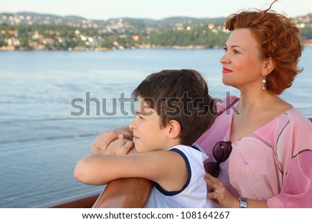 Mother and son are on board of ship and look at beautiful landscape; focus on boy