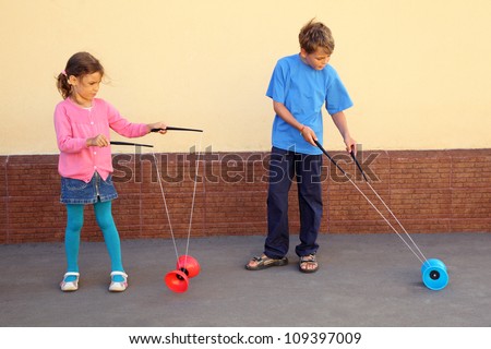 Brother and sister play with yo-yo toy at sunny day outdoor.