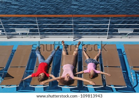 Top view of mother, son and little daughter lying at deck-chair on ship and representing starfish