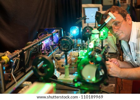 Scientist with glass demonstrate laser of microparticles, scientist in focus