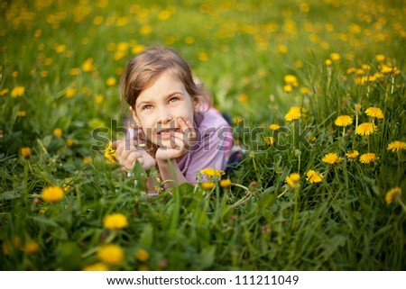 Little girl lying in grass hold flower in hand