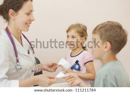 Smiling doctor gives recipe for girl and boy, focus on girl
