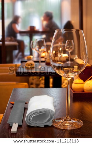 table with glasses, towel, sticks in sushi bar, couple sitting by window