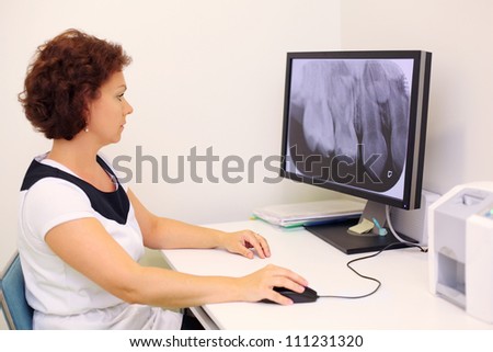 Dentist looks at big jaw x-ray image on monitor in dental clinic