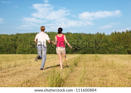 Husband and wife running in field