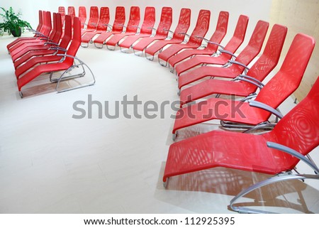 Rows of red comfortable seats in empty light room for recreation.