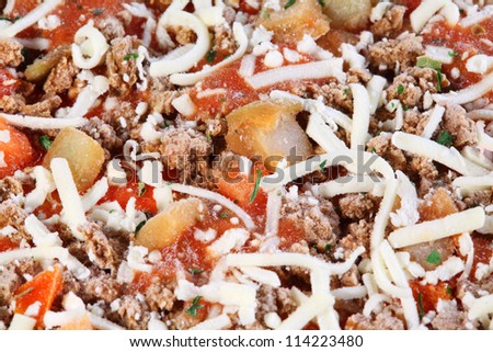 Close-up of individual frozen pizza with meat, cheese, tomatoes.