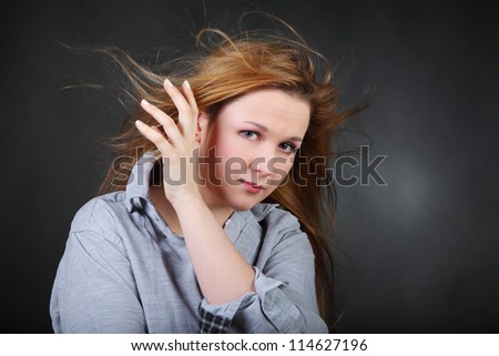 Brown-haired woman hold hair fluttering in wind in photo studio, half body