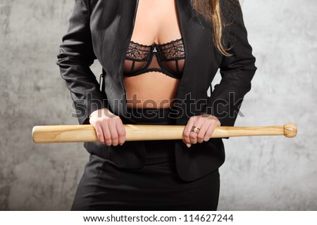 Woman in unfastened business suit in bra hold bat, half body
