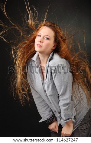 Brown hair woman pose in shirt with hair fluttering in wind in photo studio, half body
