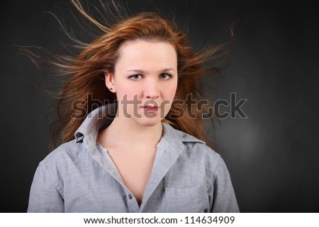 Brown hair woman with hair fluttering in wind in photo studio, half body
