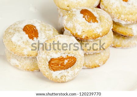 Several stacks of cookies with almond and sugar powder on plate