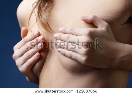 Hands of sunburnt, young woman covering breast by hands. Close up.