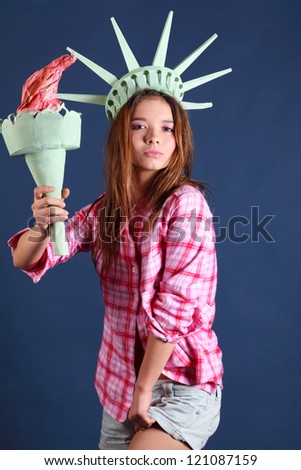 Pretty girl in pink shirt with crown and torch represents statue of liberty.