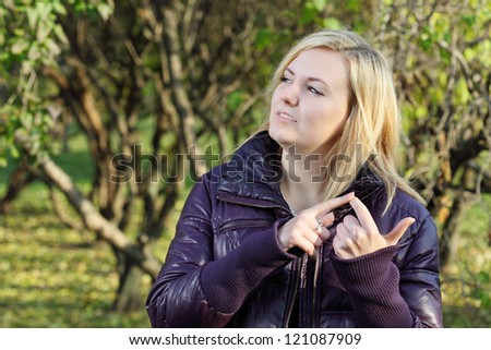 Young blonde woman dreams and counts on his fingers in park at sunny autumn day.